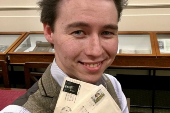 Close up of man smiling at camera and holding postcards under his chin