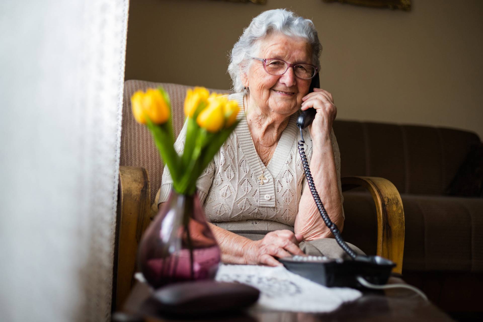 Happy senior woman talking on the phone in living room.