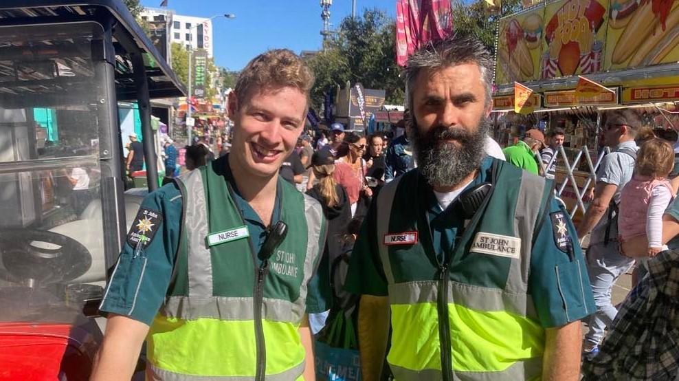 An image of two SJA volunteers at the Ekka festival in 2023. Showing two nurses stood in a crowd of people.