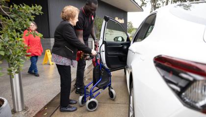 St Johns worker helping community member into vehicle.