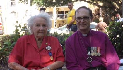 An image of Averill sat with the Bishop, smiling at the camera. Both are decorated with medals.