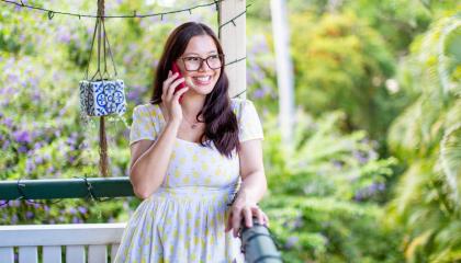 An image of Lily on the phone outside on a veranda.