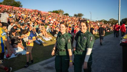 Two St Johns volunteers walking through a crowd.