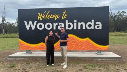 An image of two SJQ volunteers in front of the 'Welcome to Woorabinda' sign.