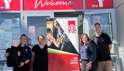 An image of four SJQ workers stood outside the front of Y Queensland, all in uniform and smiling.