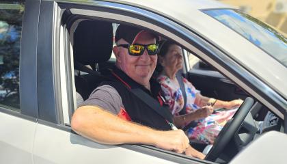 St Johns driver in a branded vehicle, smiling with a client in the vehicle.