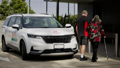 An image of a staff member and a client walking past a St John vehicle.