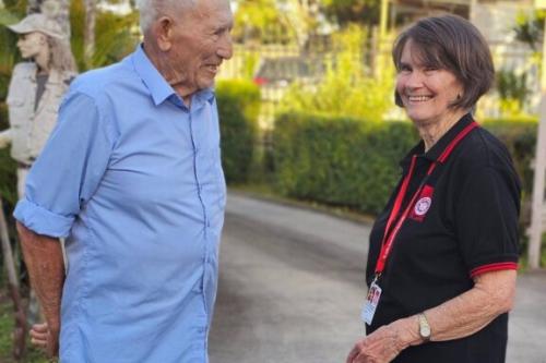 An image of client - Rico - and SJQ volunteer Rose enjoying a chat outdoors.