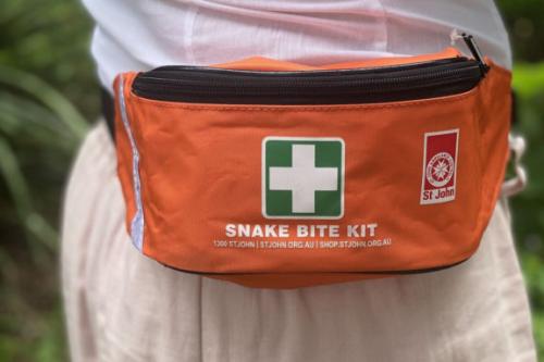 An image of the SJQ snake bite kit, worn on the waist of someone outside.