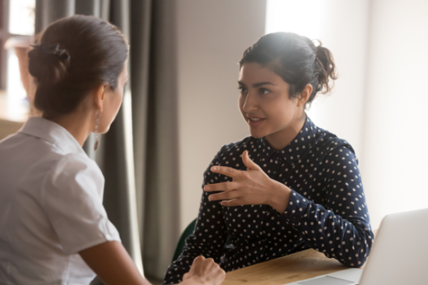 Two people sitting at a desk having a friendly discussion