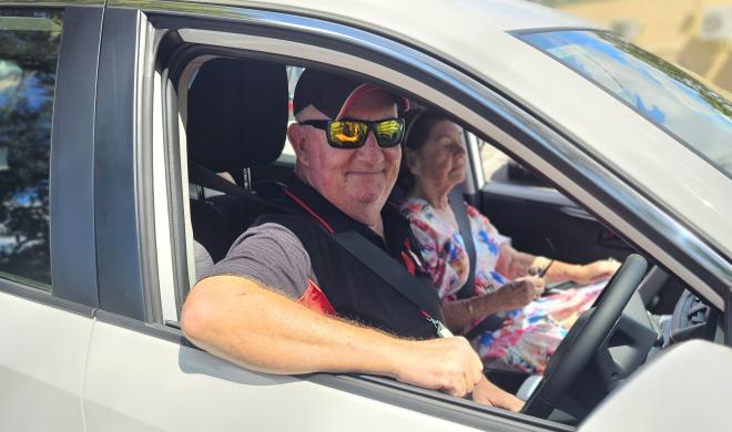 St Johns driver in a branded vehicle, smiling with a client in the vehicle.