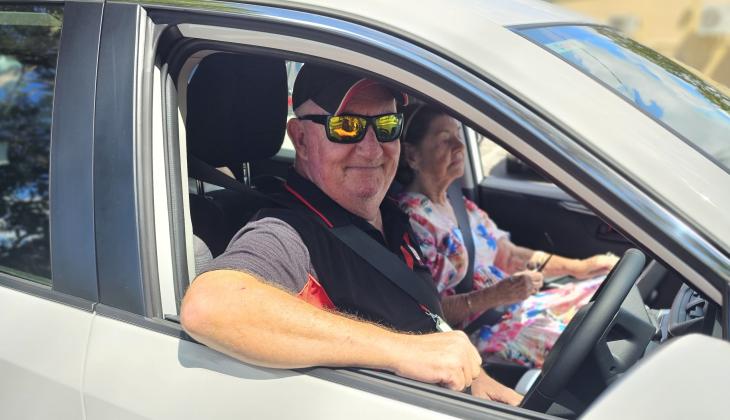 St Johns driver in a branded vehicle, smiling with a client in the vehicle.