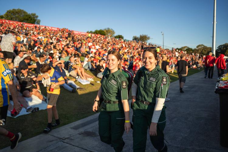 Two St Johns volunteers walking through a crowd.