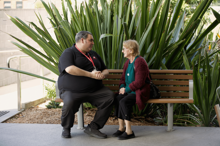 An image of a St John employee sat on a bench with a client