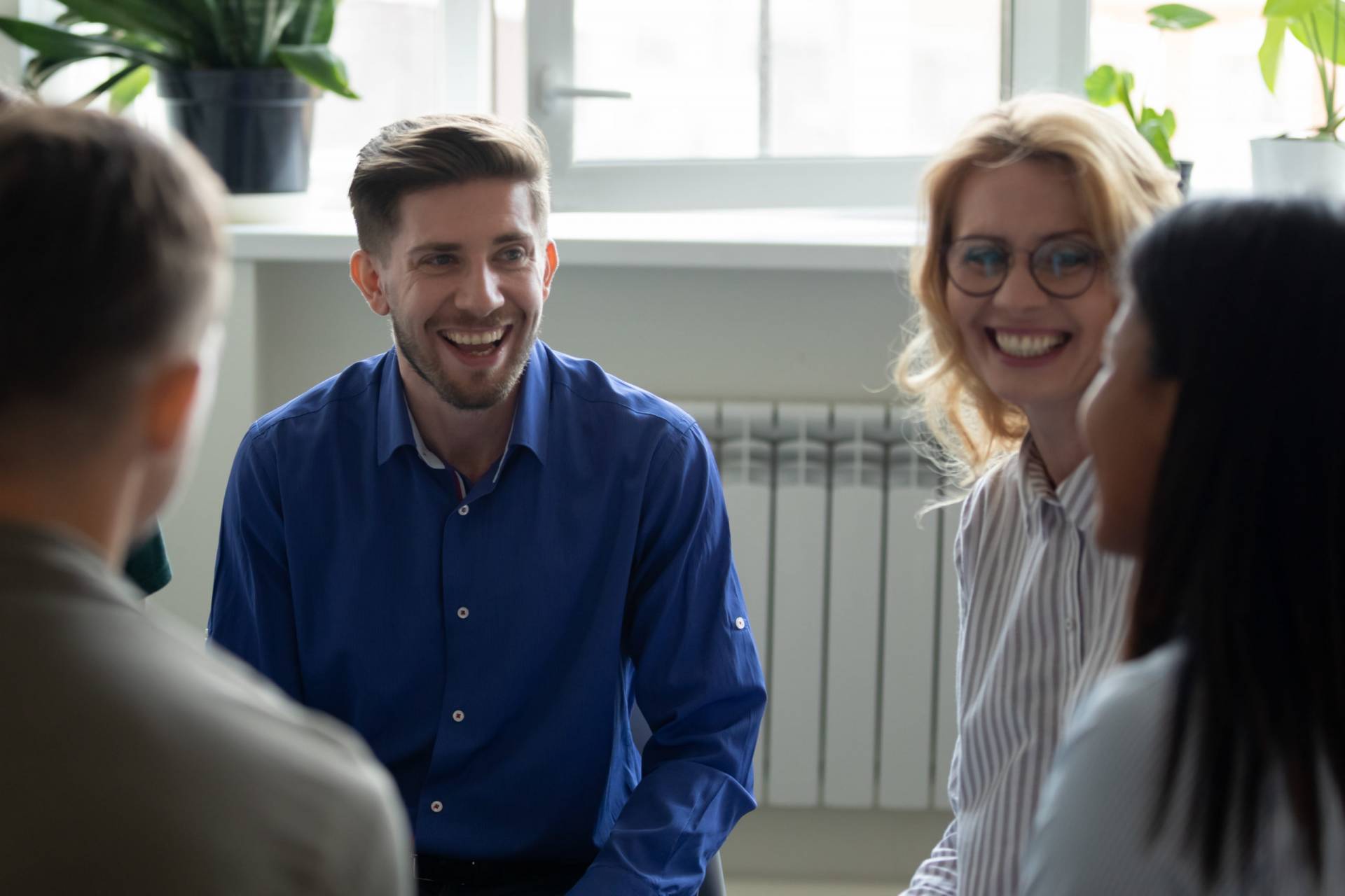 Overjoyed diverse people have fun engaged in team therapy indoors